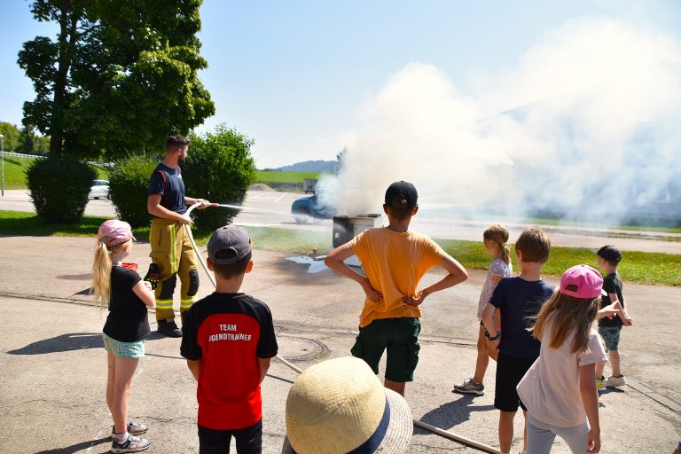Feuerwehrler zeigt Kindern, wie man einen Brand löscht